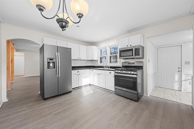 kitchen featuring light hardwood / wood-style flooring, pendant lighting, stainless steel appliances, white cabinets, and sink