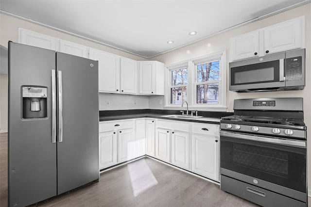 kitchen featuring stainless steel appliances, white cabinetry, hardwood / wood-style flooring, and sink