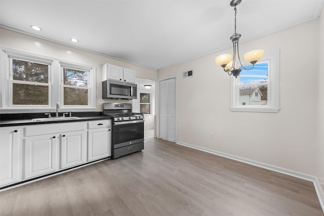 kitchen with pendant lighting, an inviting chandelier, white cabinets, appliances with stainless steel finishes, and sink