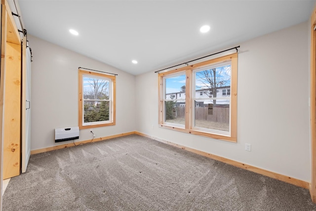 carpeted spare room with lofted ceiling, a wealth of natural light, and a barn door