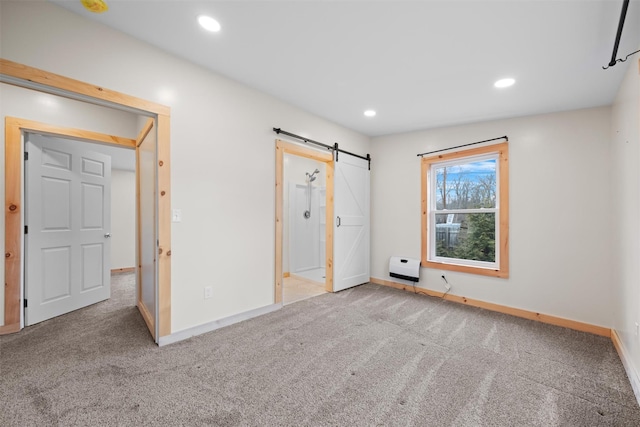 unfurnished bedroom with a barn door, heating unit, and light carpet