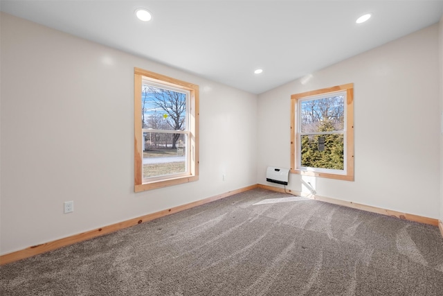 spare room featuring heating unit, vaulted ceiling, carpet flooring, and plenty of natural light