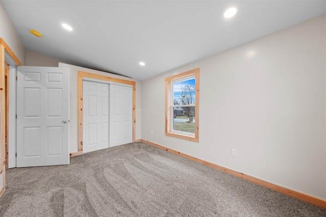 unfurnished bedroom with lofted ceiling, a closet, and carpet floors