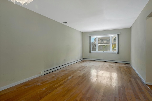 unfurnished room with a baseboard heating unit and light hardwood / wood-style floors