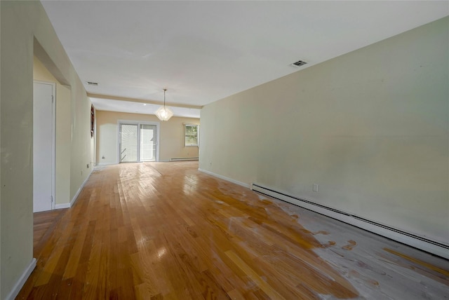 empty room featuring a baseboard heating unit and light hardwood / wood-style flooring