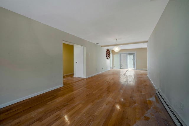 unfurnished room featuring baseboard heating and light hardwood / wood-style floors