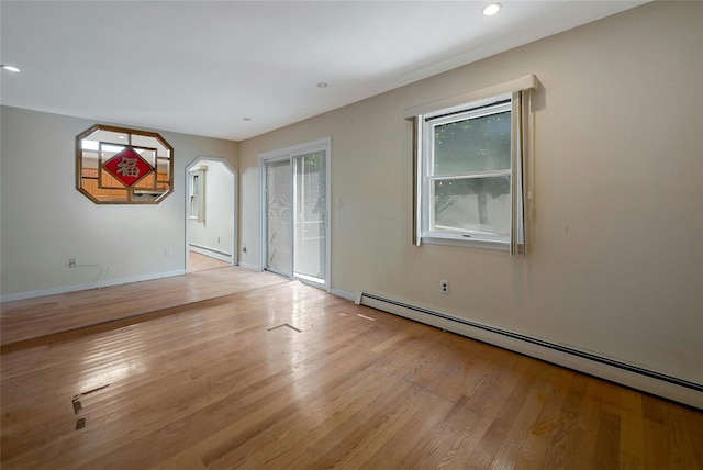 spare room featuring a baseboard radiator and light hardwood / wood-style floors