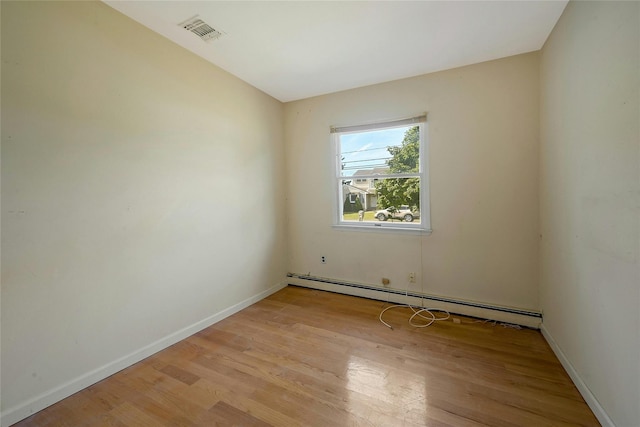 unfurnished room with baseboard heating and light hardwood / wood-style floors