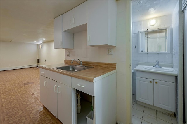 kitchen with white cabinets, decorative backsplash, a baseboard radiator, and sink