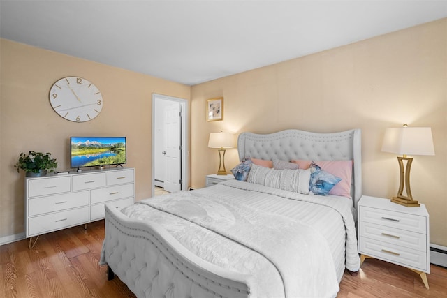 bedroom featuring a baseboard heating unit and wood-type flooring