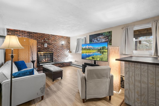 living room featuring light wood-type flooring, baseboard heating, a textured ceiling, and a fireplace