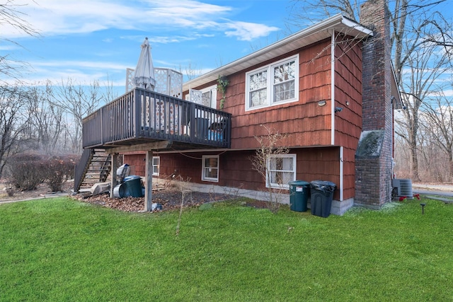 back of house featuring central AC unit, a deck, and a lawn