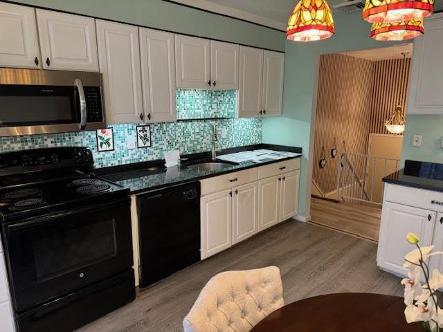 kitchen featuring decorative light fixtures, black appliances, sink, light wood-type flooring, and white cabinets