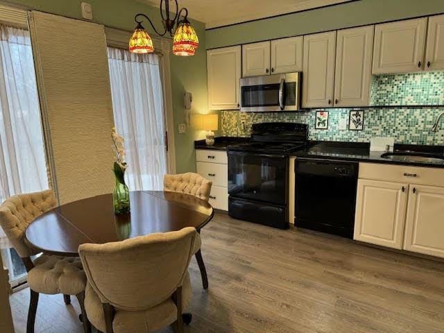 kitchen with light hardwood / wood-style floors, black appliances, pendant lighting, sink, and white cabinets