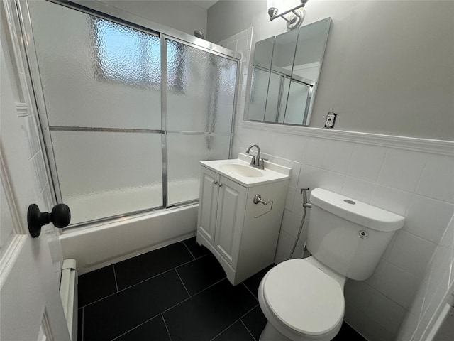 full bathroom with toilet, tile patterned flooring, combined bath / shower with glass door, tile walls, and vanity