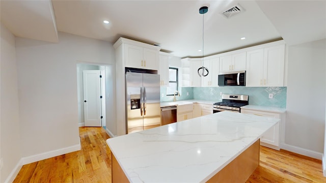 kitchen with decorative light fixtures, decorative backsplash, light wood-type flooring, stainless steel appliances, and white cabinets