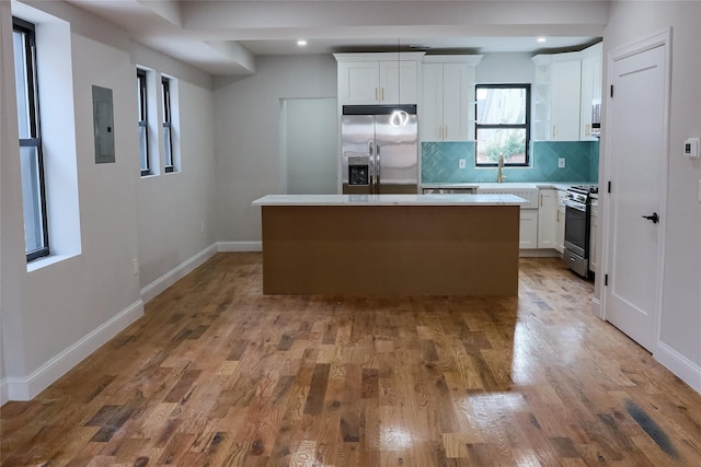 kitchen featuring decorative backsplash, appliances with stainless steel finishes, white cabinetry, and a center island