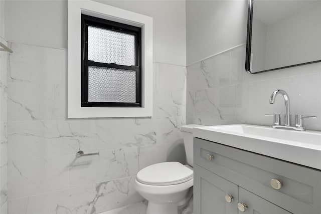 bathroom featuring toilet, vanity, and tile walls