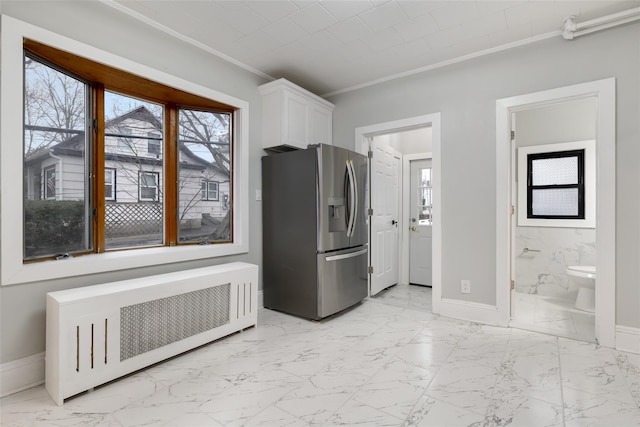 kitchen featuring crown molding, radiator, a healthy amount of sunlight, white cabinets, and stainless steel fridge