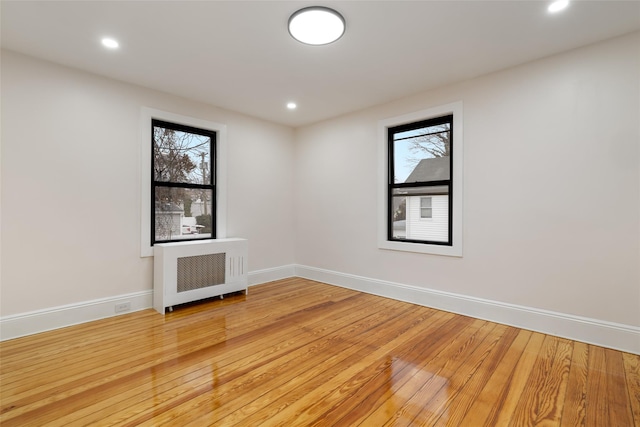 empty room with radiator heating unit and hardwood / wood-style flooring