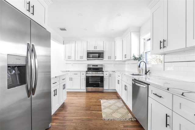 kitchen with stainless steel appliances, dark hardwood / wood-style flooring, light stone counters, white cabinets, and sink