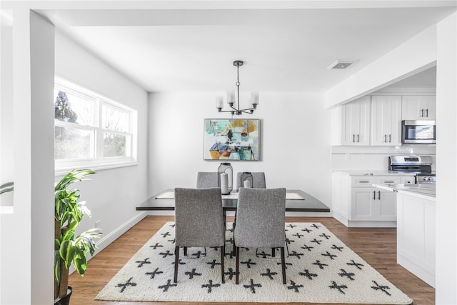 dining space with wood-type flooring and a notable chandelier