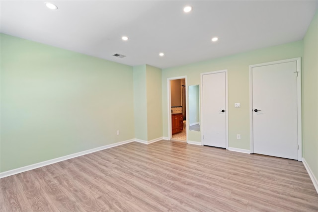 unfurnished bedroom featuring ensuite bathroom and light wood-type flooring