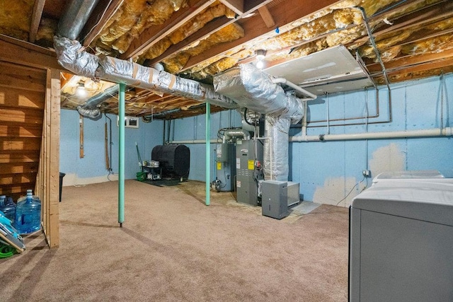 basement featuring water heater, independent washer and dryer, and carpet