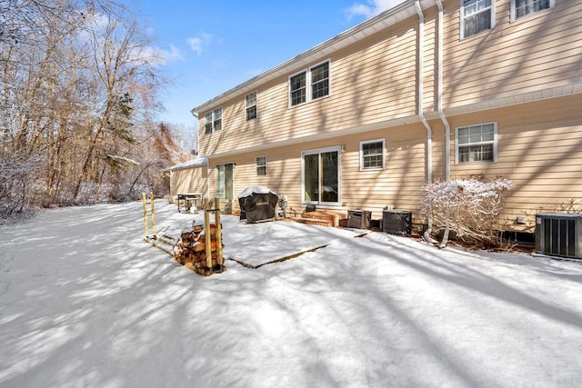 snow covered back of property featuring central AC