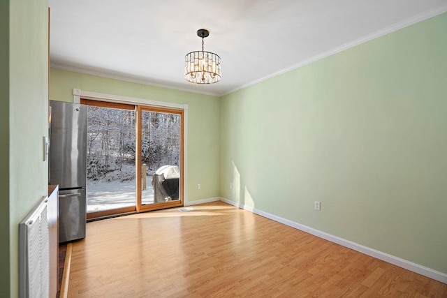 spare room featuring ornamental molding, a chandelier, and light hardwood / wood-style flooring