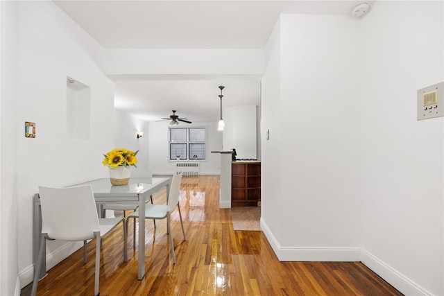 dining space featuring radiator heating unit, ceiling fan, and hardwood / wood-style flooring