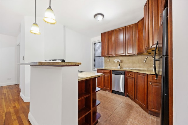 kitchen featuring sink, decorative light fixtures, dishwasher, backsplash, and light stone countertops