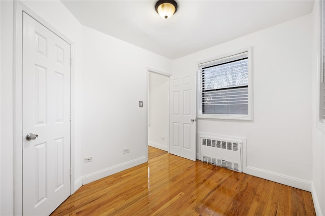 unfurnished room featuring wood-type flooring and radiator