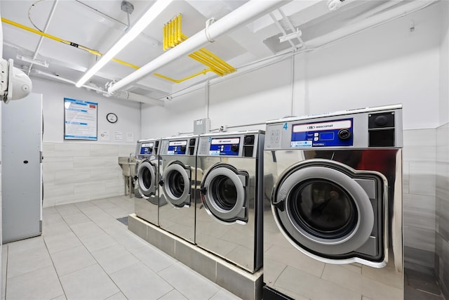 clothes washing area with washer and dryer and light tile patterned floors