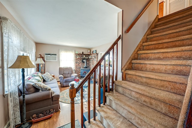 stairway featuring a wall unit AC, baseboard heating, a wood stove, and hardwood / wood-style flooring