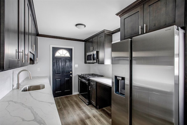 kitchen with hardwood / wood-style floors, appliances with stainless steel finishes, crown molding, sink, and tasteful backsplash