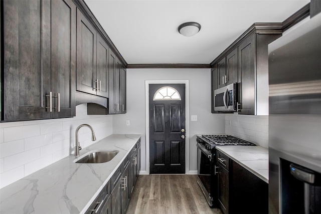 kitchen featuring stainless steel appliances, light stone countertops, ornamental molding, sink, and backsplash