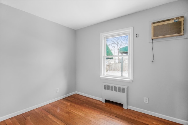 unfurnished room with wood-type flooring, radiator heating unit, and a wall mounted AC