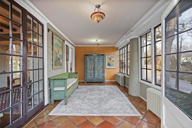 entryway with crown molding, radiator, and tile patterned floors