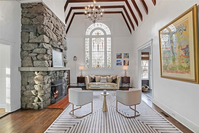 living room featuring high vaulted ceiling, dark hardwood / wood-style floors, a notable chandelier, and a fireplace