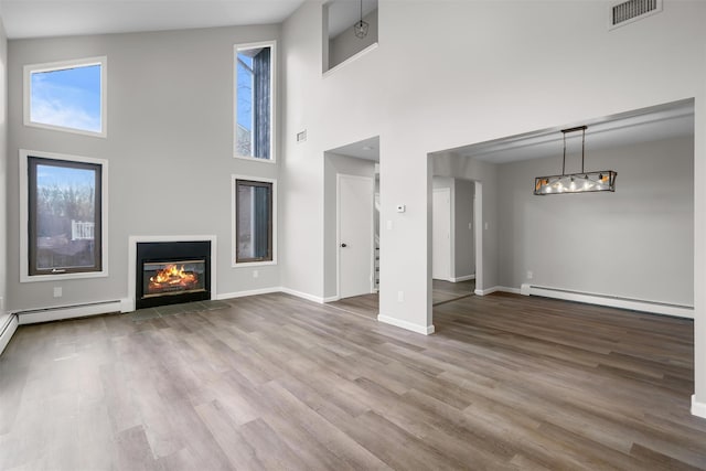 unfurnished living room featuring high vaulted ceiling, a baseboard radiator, and hardwood / wood-style floors