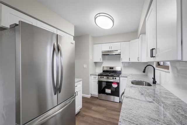 kitchen with sink, appliances with stainless steel finishes, white cabinets, dark hardwood / wood-style flooring, and light stone counters