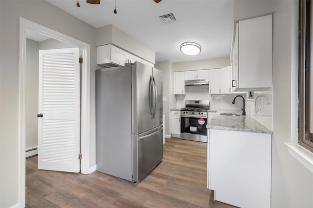 kitchen with sink, white cabinetry, hardwood / wood-style flooring, stainless steel appliances, and a baseboard radiator