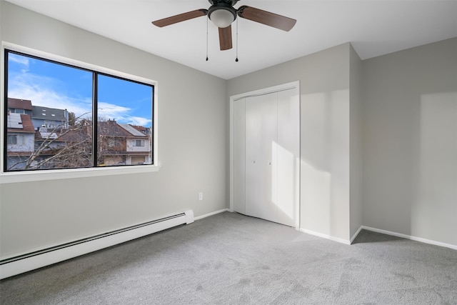 unfurnished bedroom featuring ceiling fan, a baseboard heating unit, a closet, and carpet flooring