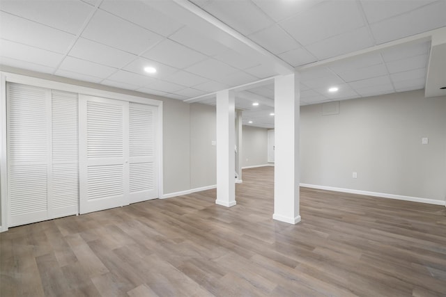 basement featuring a paneled ceiling and hardwood / wood-style flooring