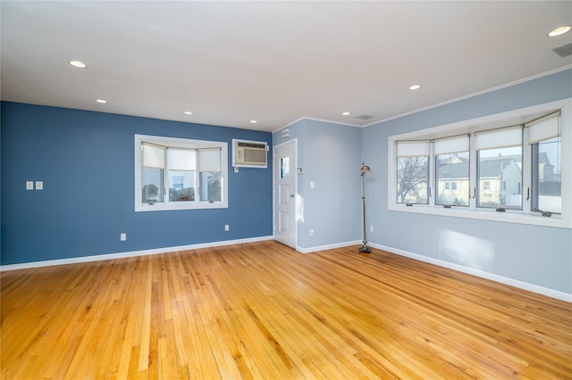 spare room featuring crown molding, a wall mounted AC, and light hardwood / wood-style floors