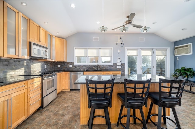 kitchen featuring lofted ceiling, a breakfast bar area, a kitchen island, a wall unit AC, and stainless steel appliances