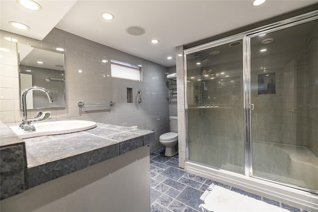 bathroom with walk in shower, vanity, toilet, and tile walls