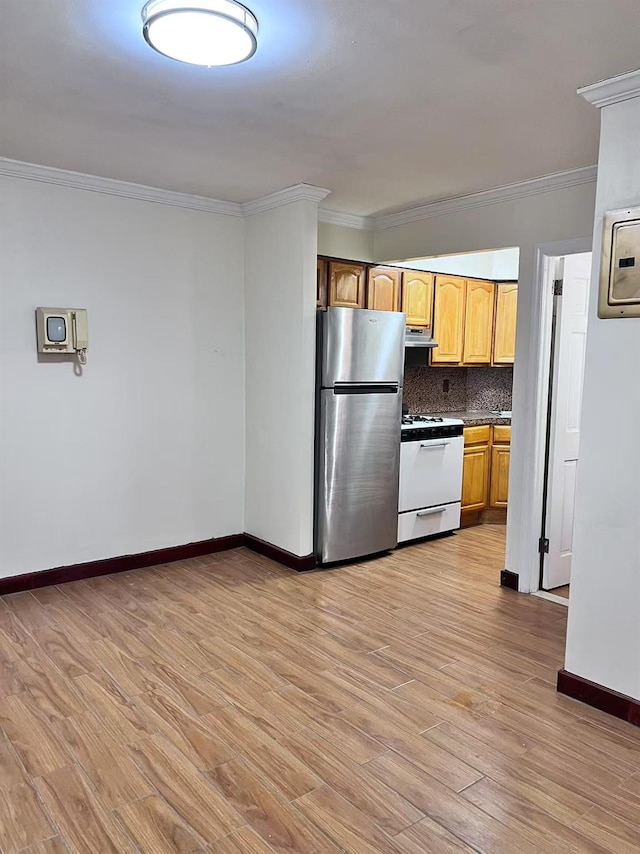 kitchen with light wood-type flooring, ornamental molding, stainless steel fridge, decorative backsplash, and white gas range