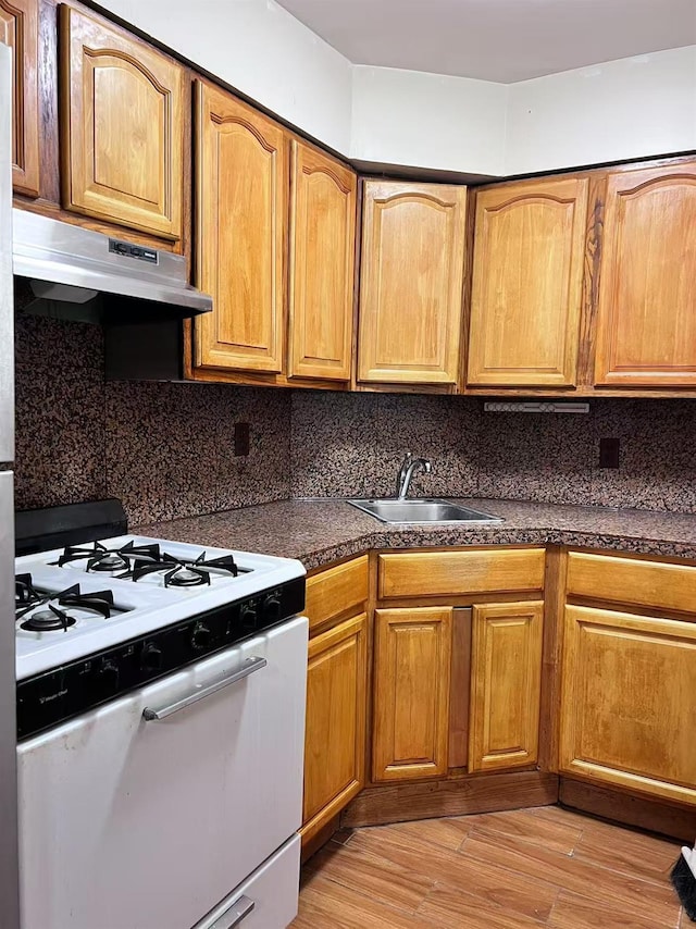 kitchen with sink, white range with gas stovetop, tasteful backsplash, and light hardwood / wood-style flooring